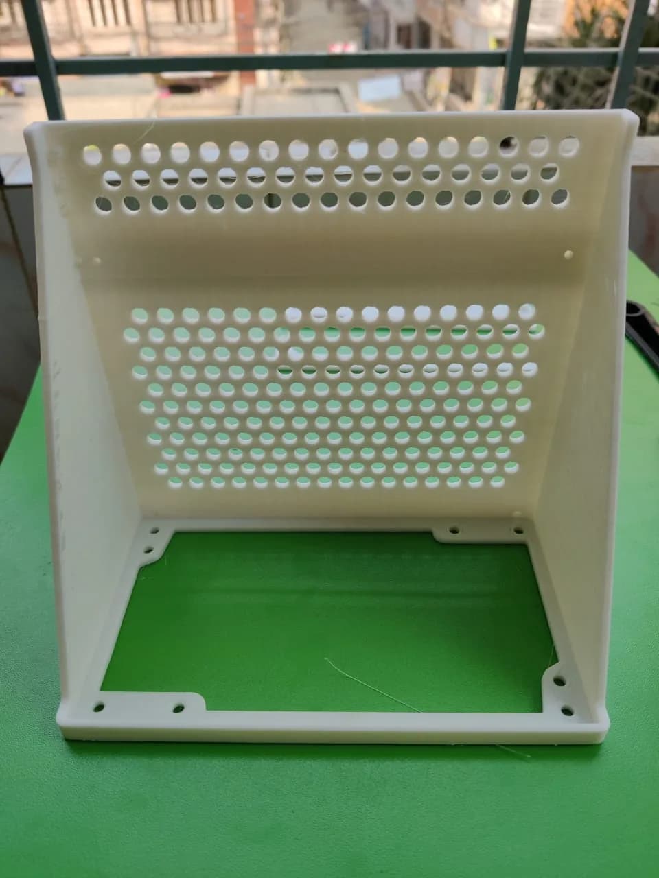 White printed PSU bracket standing open, showing the vented back panel and the base frame with corner screw holes