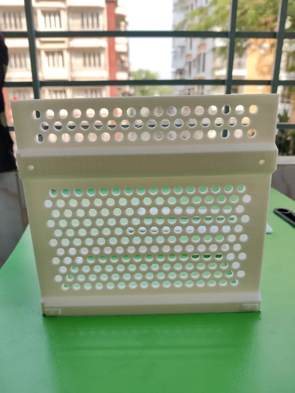 Front of the white 3D printed ATX PSU bracket with rows of round vent holes