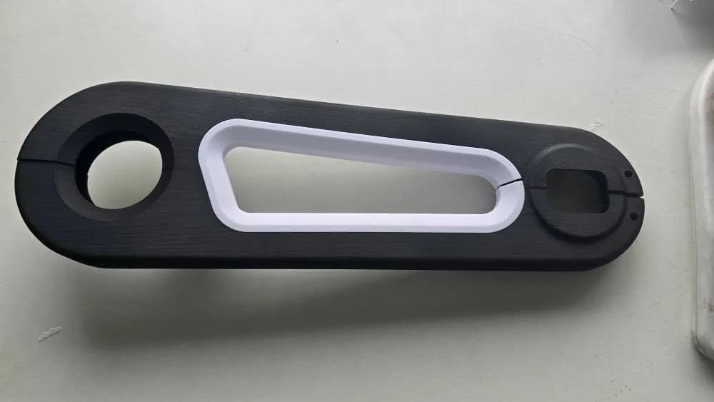 Assembled black and white 3D printed bicycle chain cover lying flat on a white surface