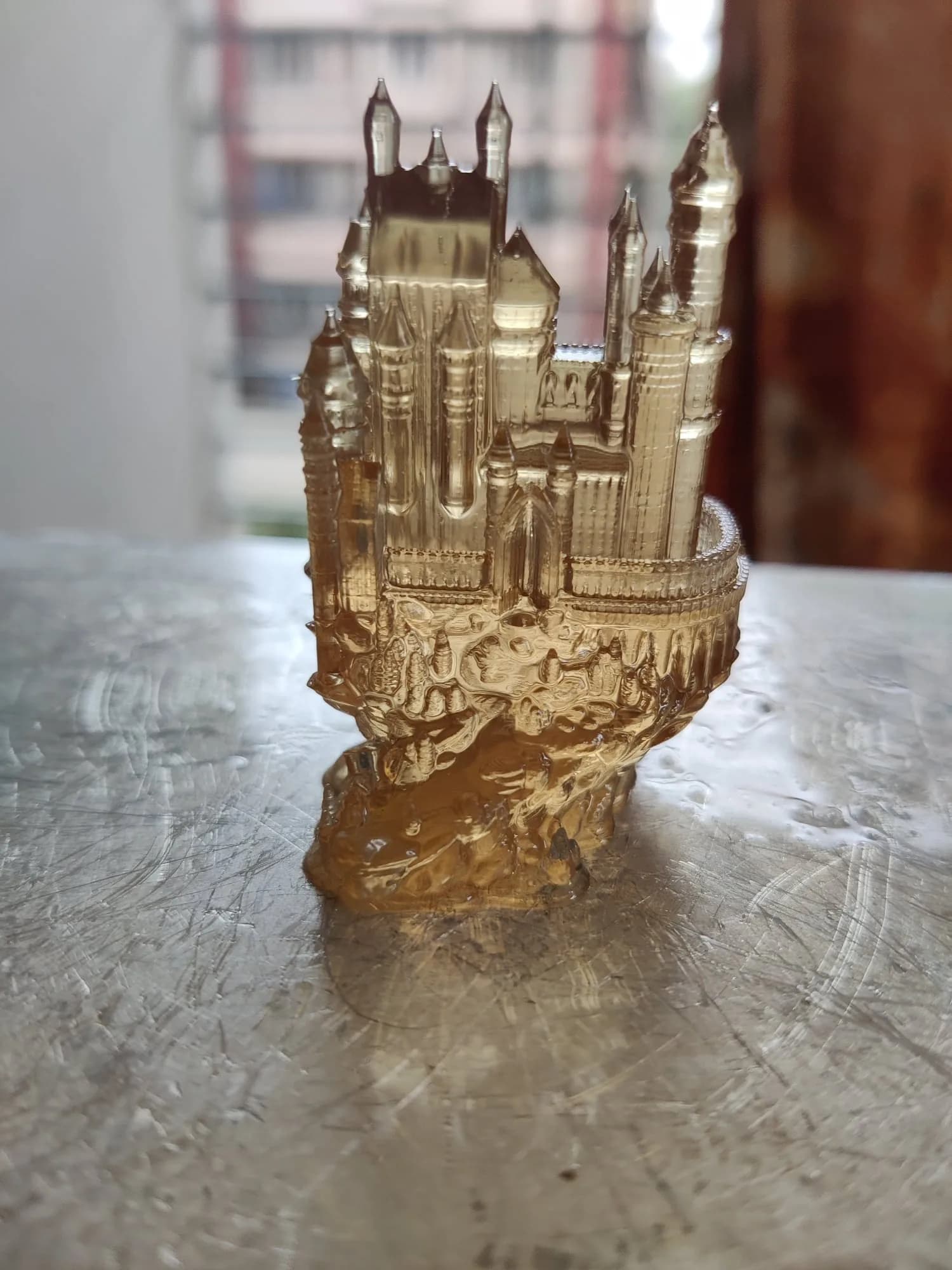 Clear resin castle model on a metal table, glass-like surface with spires and crenellated wall