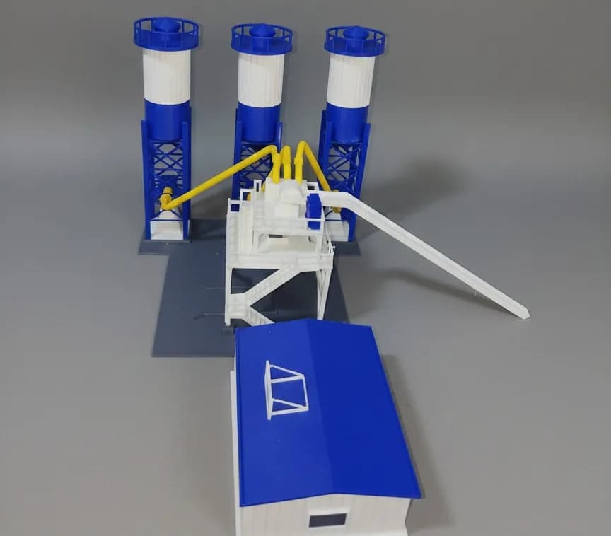 Front view of the concrete batching plant model with the blue-roofed site office in front of the mixer tower and silos