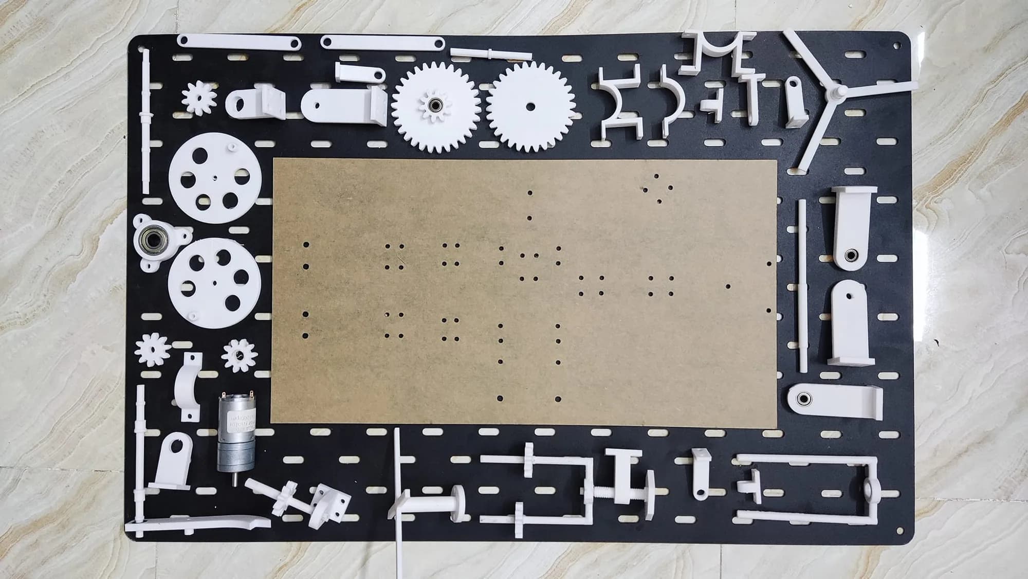 All printed parts of the machine model laid out around a base plate with its drilled mounting holes