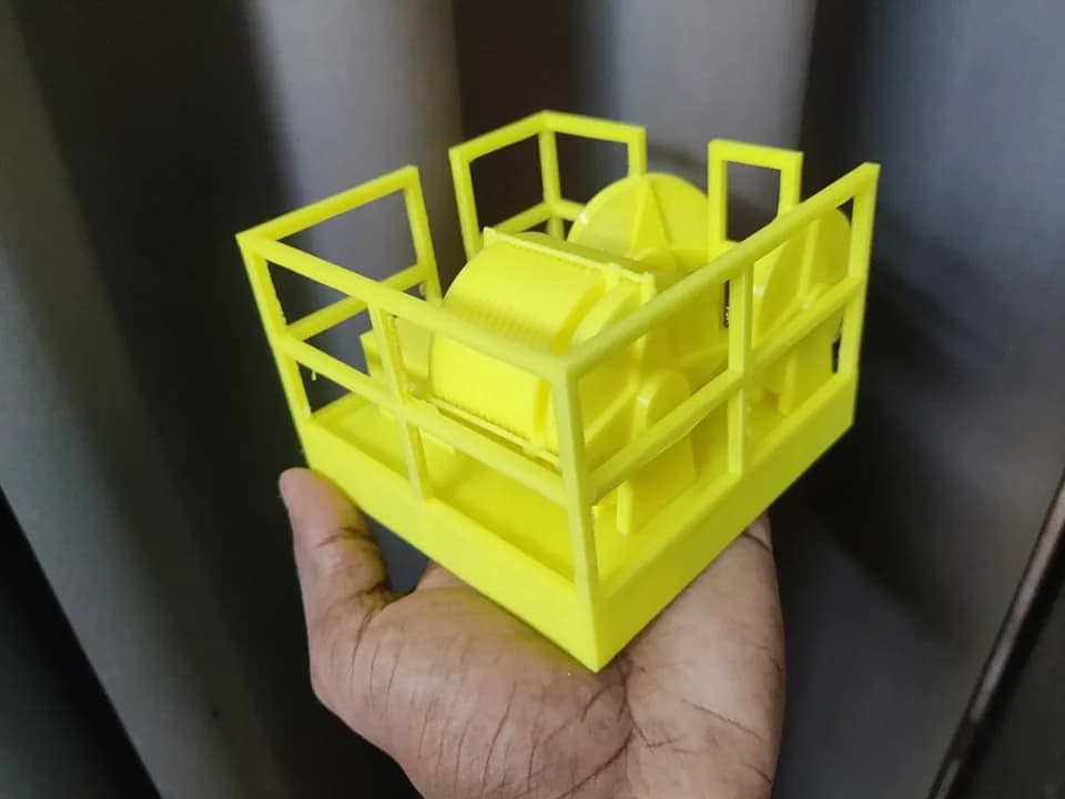 Side view of the 3D printed crown block model with a grooved drum and flanged sheaves inside a railing frame