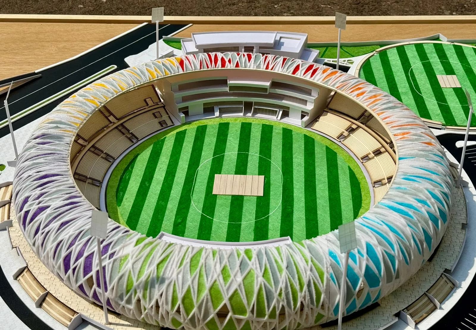 Stadium bowl of the model with stepped stands, striped field and pitch inside the colourful lattice ring