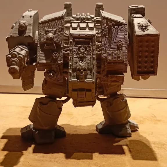 Front view of the grey Dreadnought figure showing the central armour panel, skull emblems and weapon arms