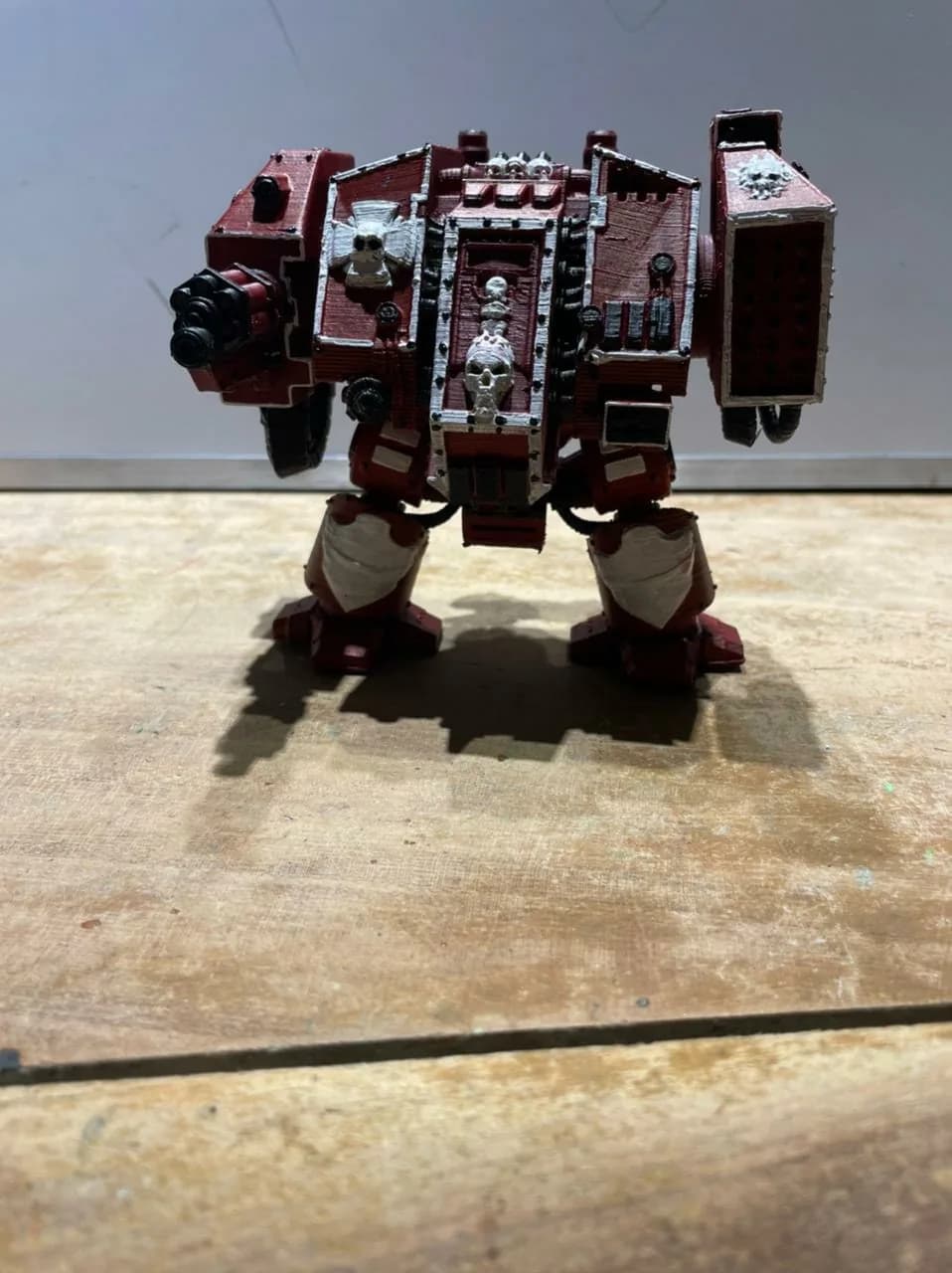Front view of the painted red Dreadnought figure on a wooden board