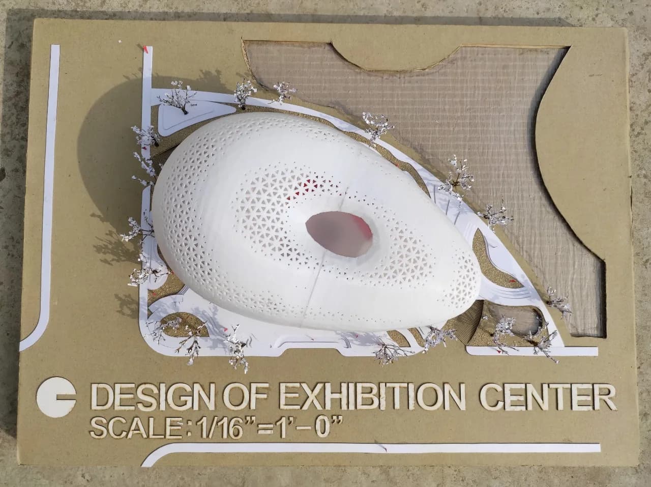 Top view of the Purbachal exhibition centre model: perforated shell, white paths set into the board and a recessed textured area