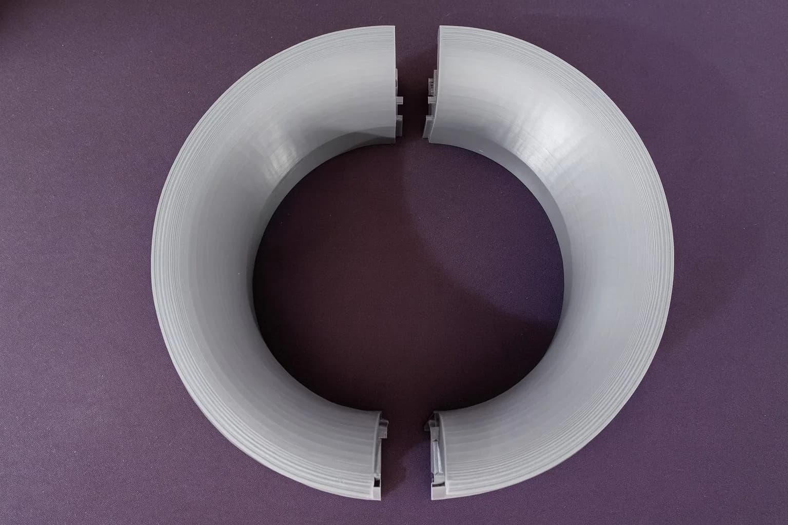 Top-down view of the grey 3D printed funnel collar halves forming a ring, with the joint keys at the two split lines