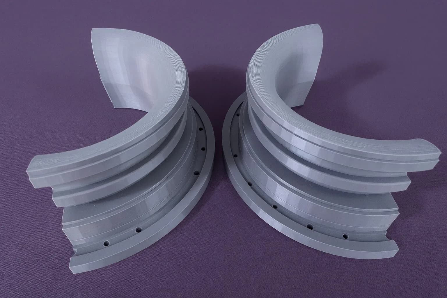 The two printed funnel collar halves pulled apart on a purple surface, showing the ring of holes in each flange
