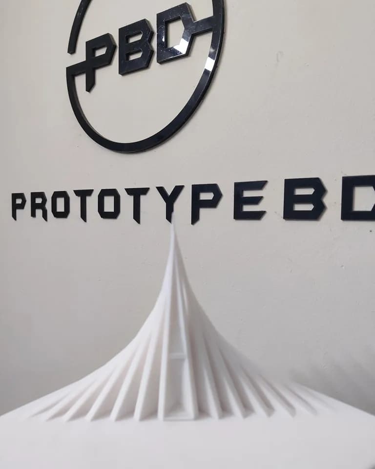 Front of the white National Memorial model in front of the PrototypeBD wall logo