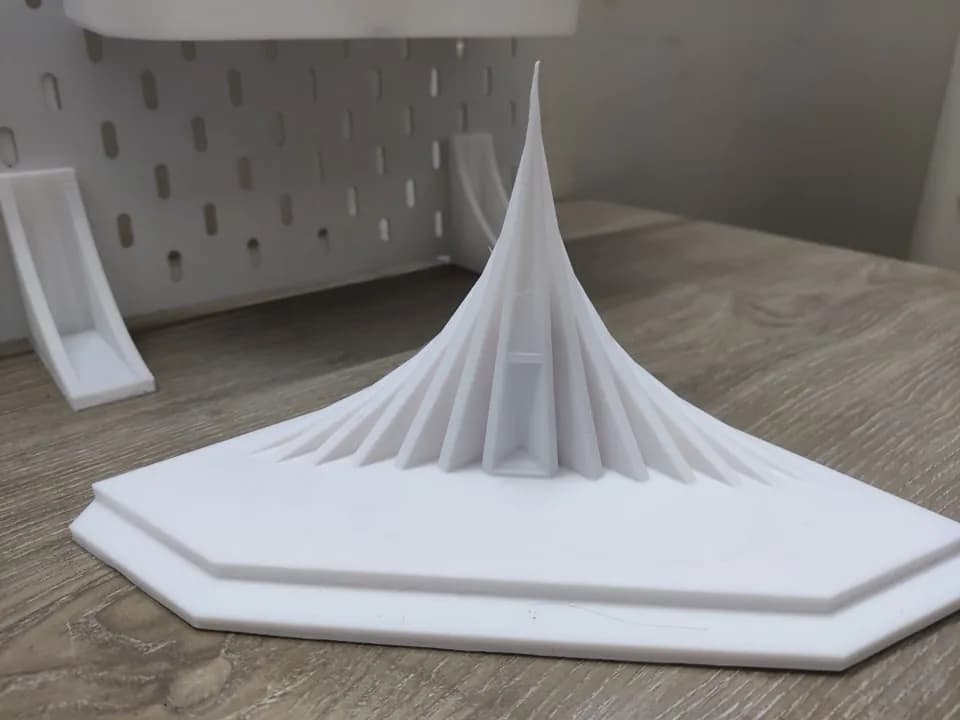 National Memorial miniature on a wooden shelf, triangular planes rising to a sharp peak above a stepped base