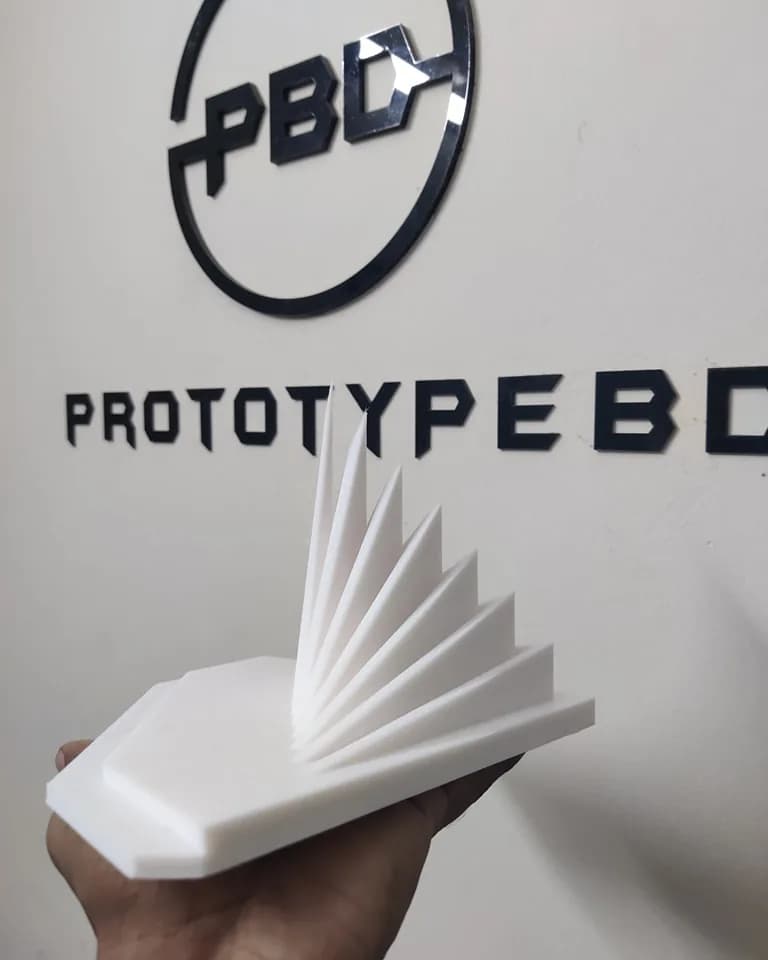 National Memorial miniature held in one hand below the PrototypeBD logo on the workshop wall