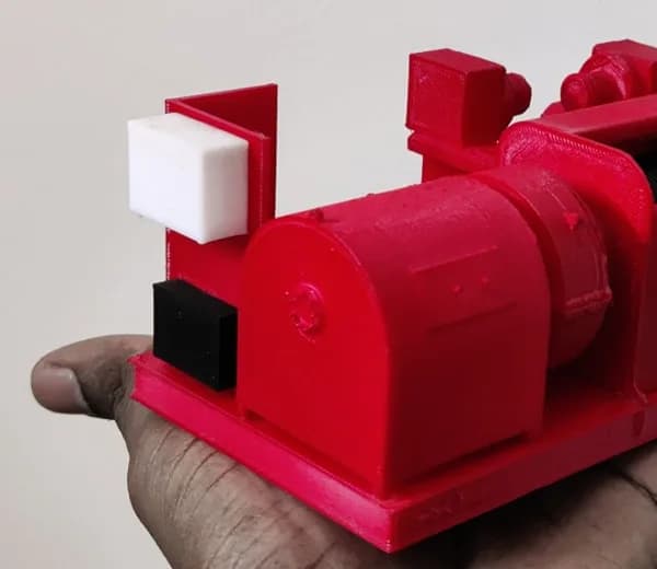 Close-up of one end of the oil-rig equipment model: rounded red motor housing, bracket and white and black blocks