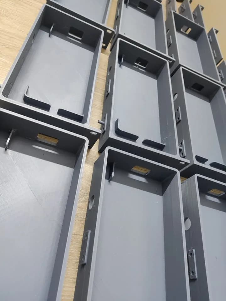 Close-up of 3D printed trays showing the retaining clips, side holes and mounting tabs on the walls