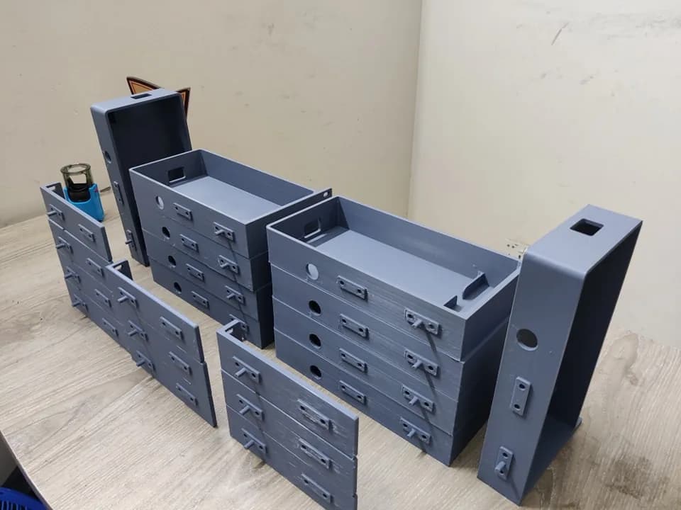 Grey printed rack mount trays stacked with side rails and end plates showing mounting tabs and locating pins