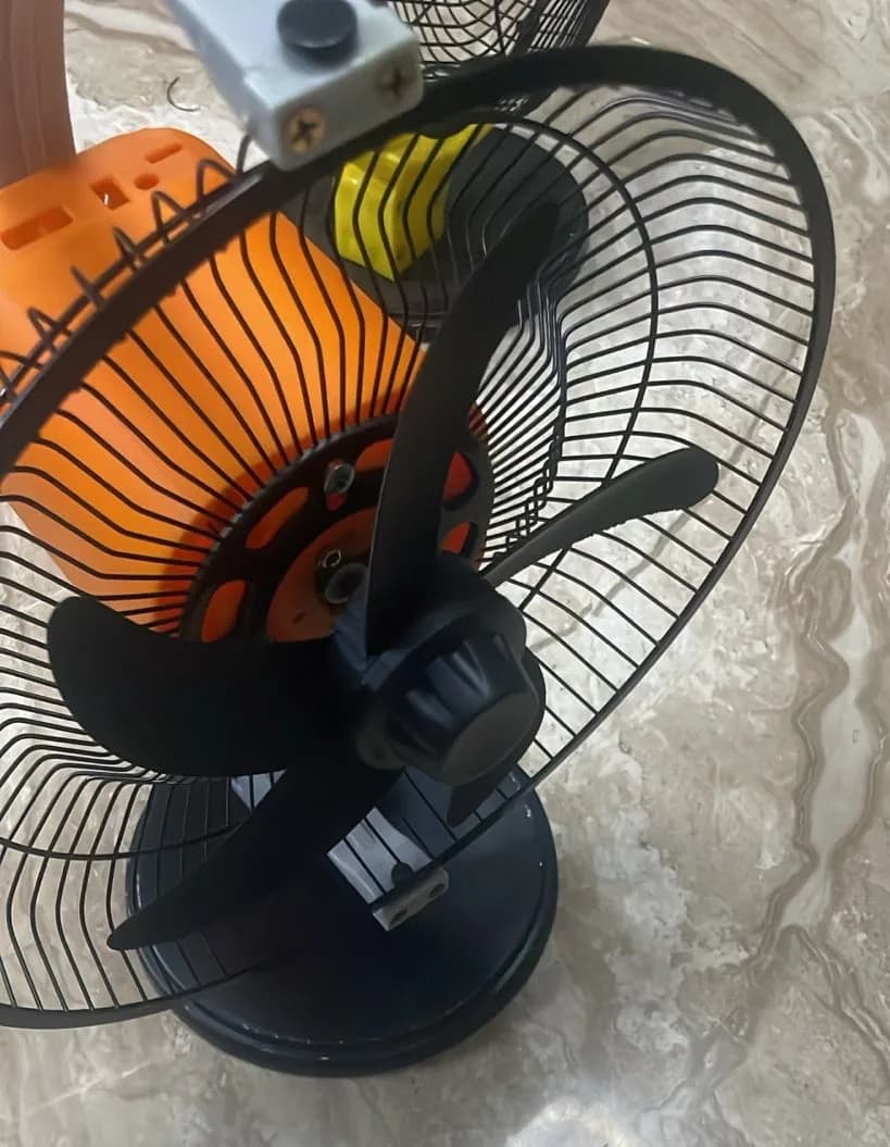 Assembled rechargeable fan prototype with the printed black rotor and orange motor housing behind a wire guard on a stand