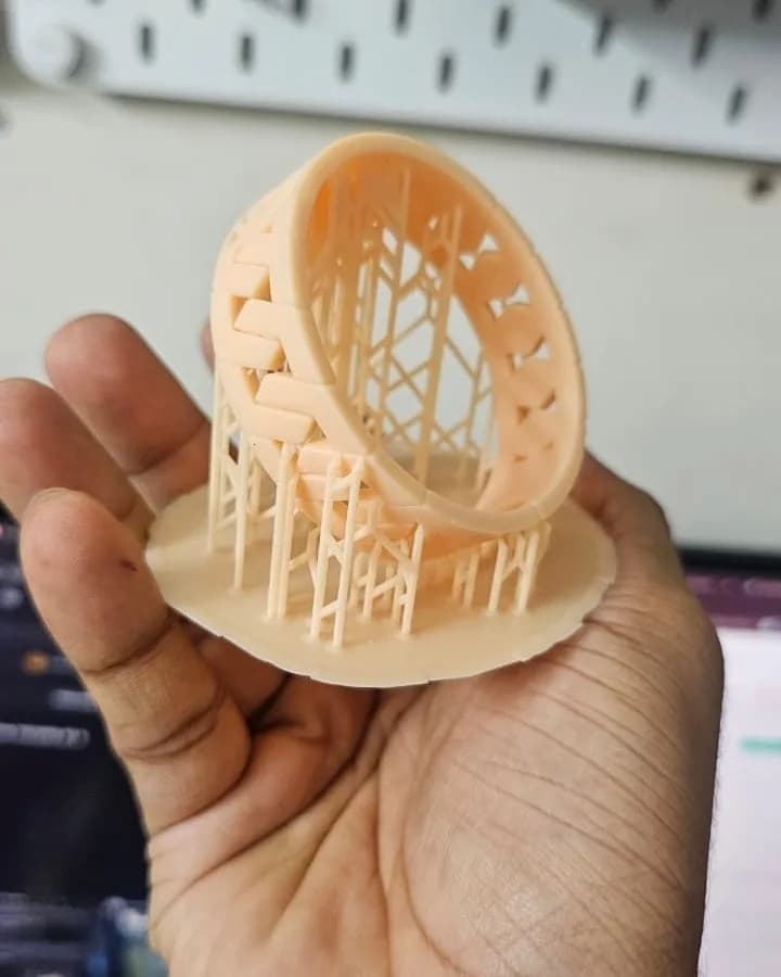 Resin bangle standing on its build-plate raft and a lattice of thin supports after printing