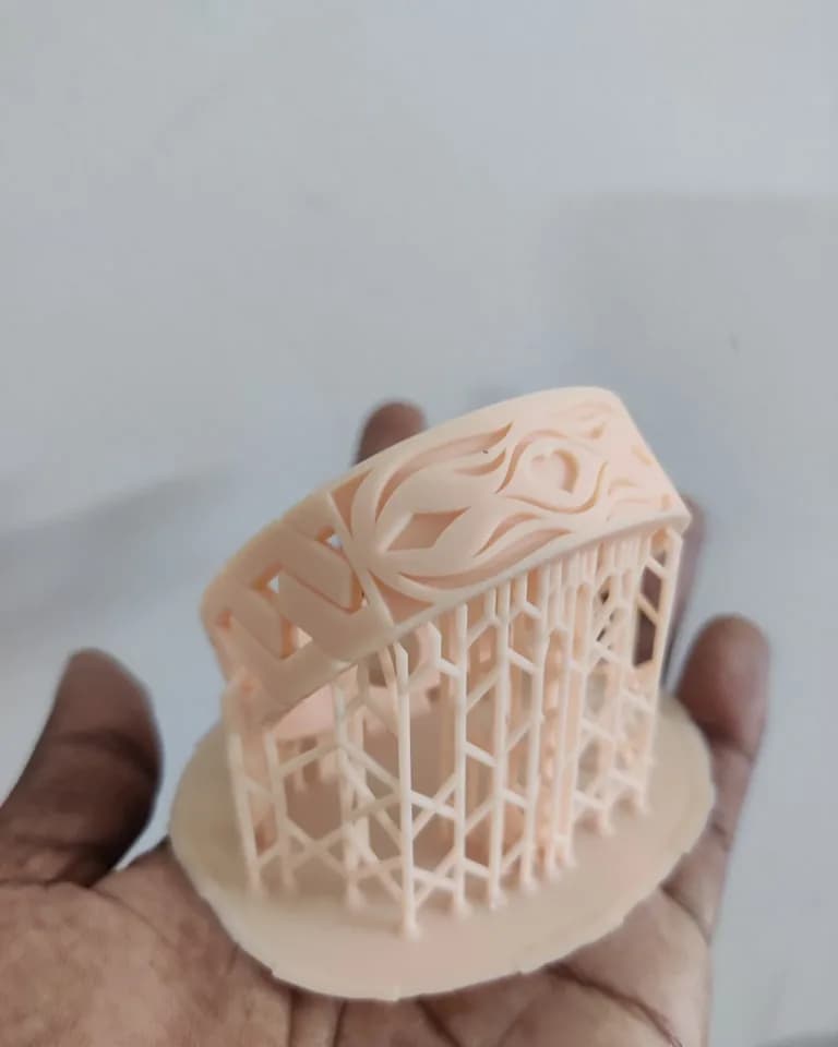 Bangle on its supports seen from the side, tilted on the build plate so the patterned face is support-free