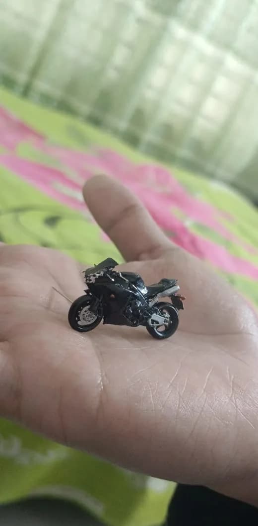 Miniature sport bike resting on fingers, front brake disc and fairing in focus