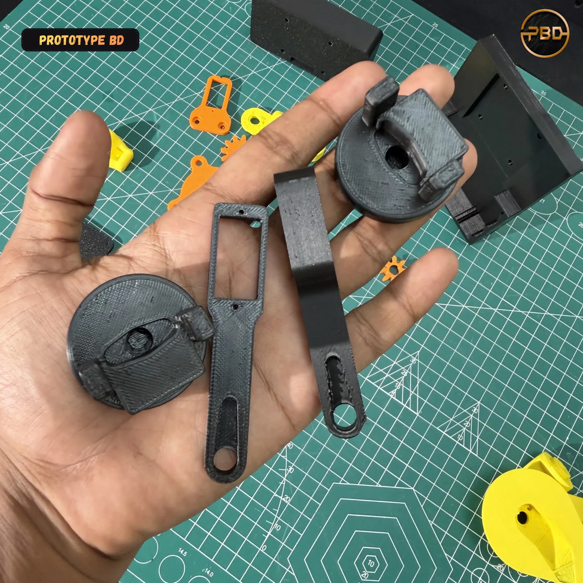 Hand holding black 3D printed turntable discs and slotted arm links that carry the servos