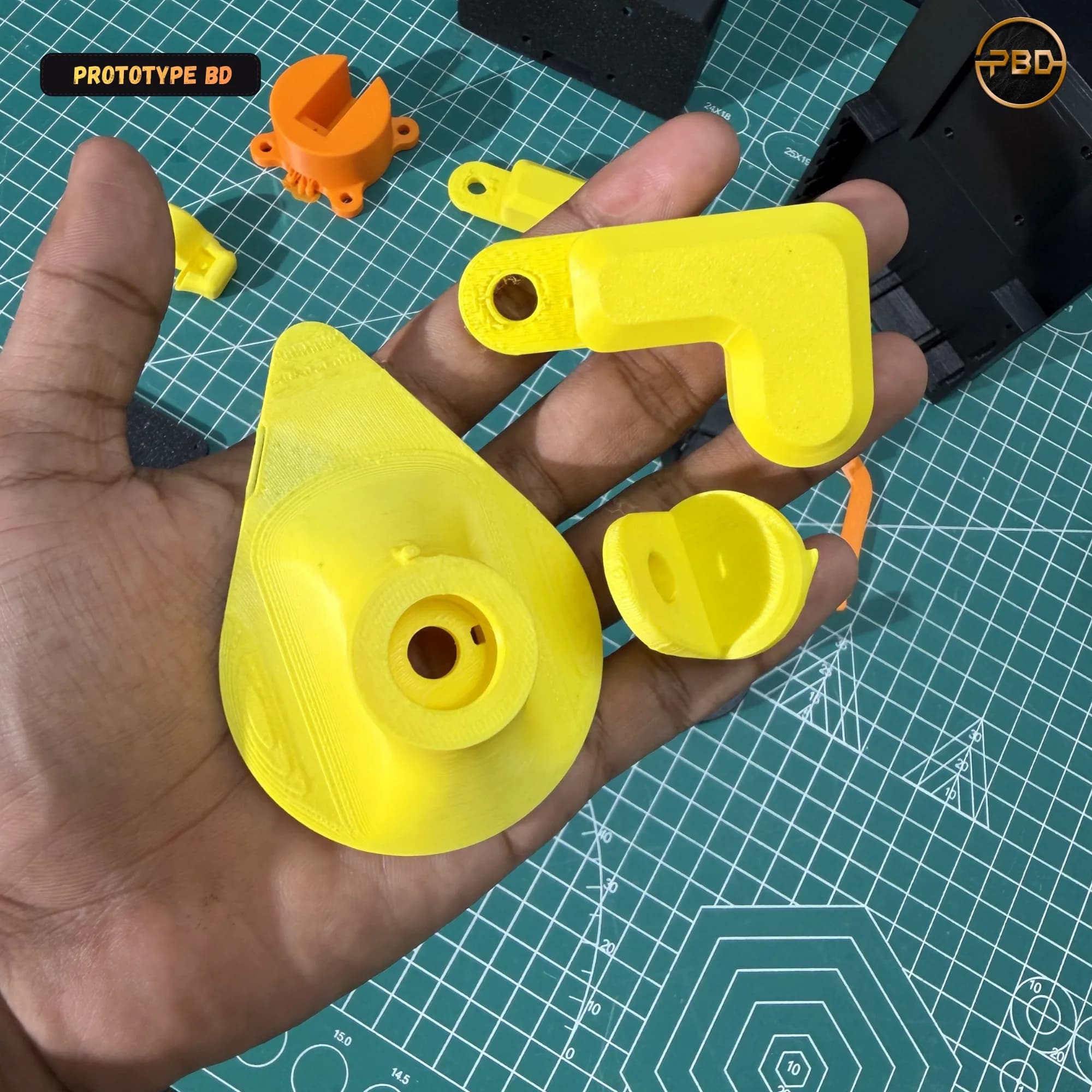 Hand holding the yellow 3D printed shoulder cone and elbow parts of the robotic arm