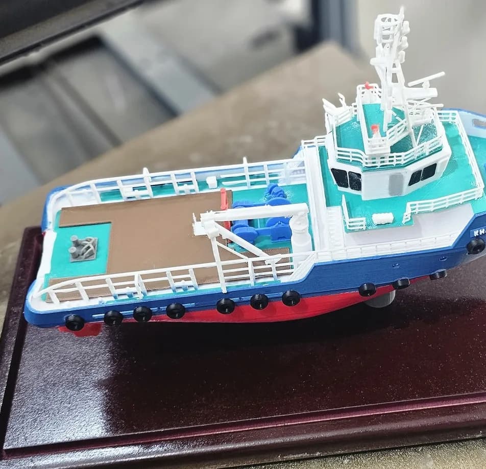 View from above of the tugboat model's aft deck with the brown working area, blue winches, crane and white railings