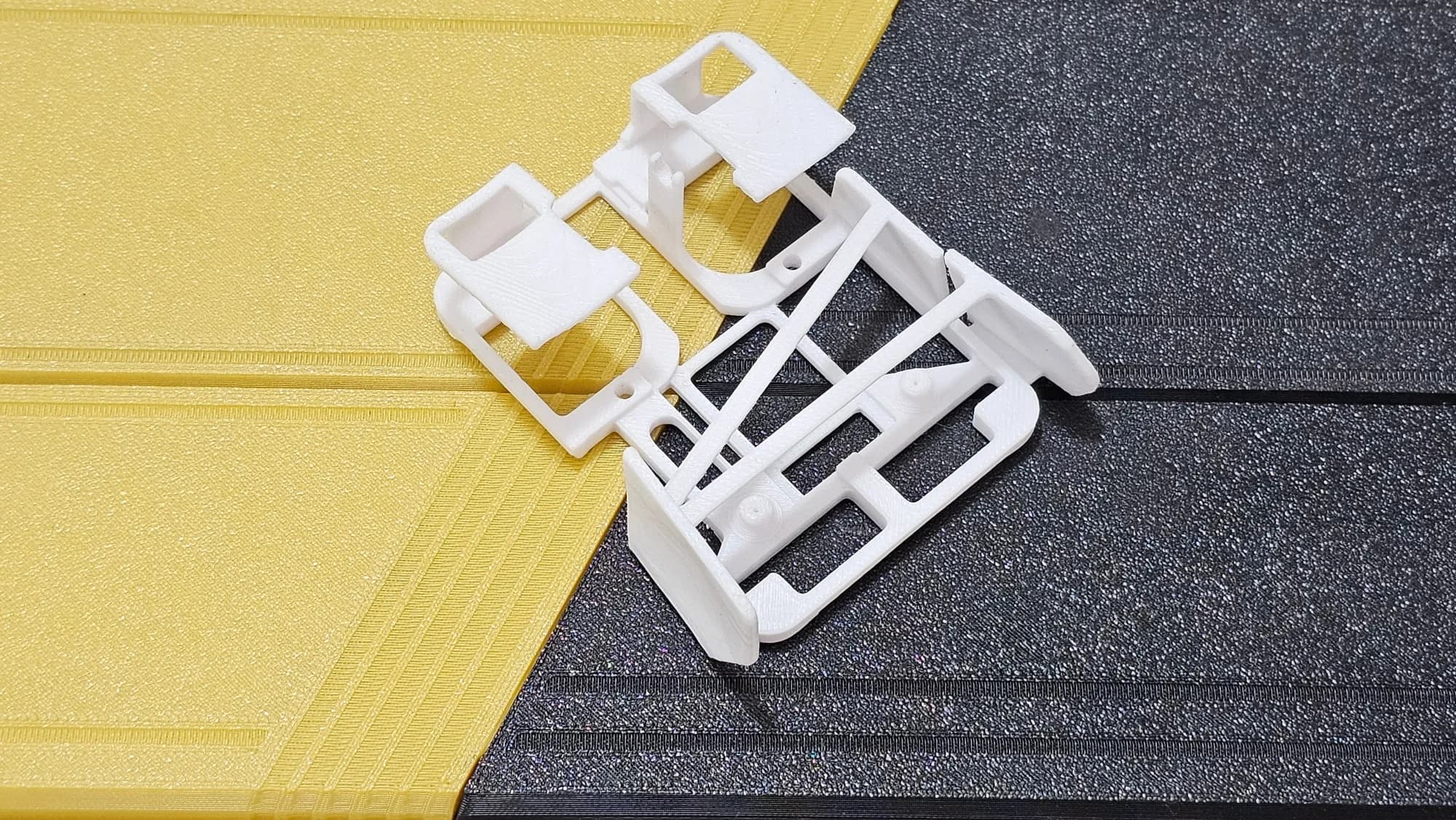 Top view of the empty white 3D printed lightweight mouse shell with diagonal braces and front button pads