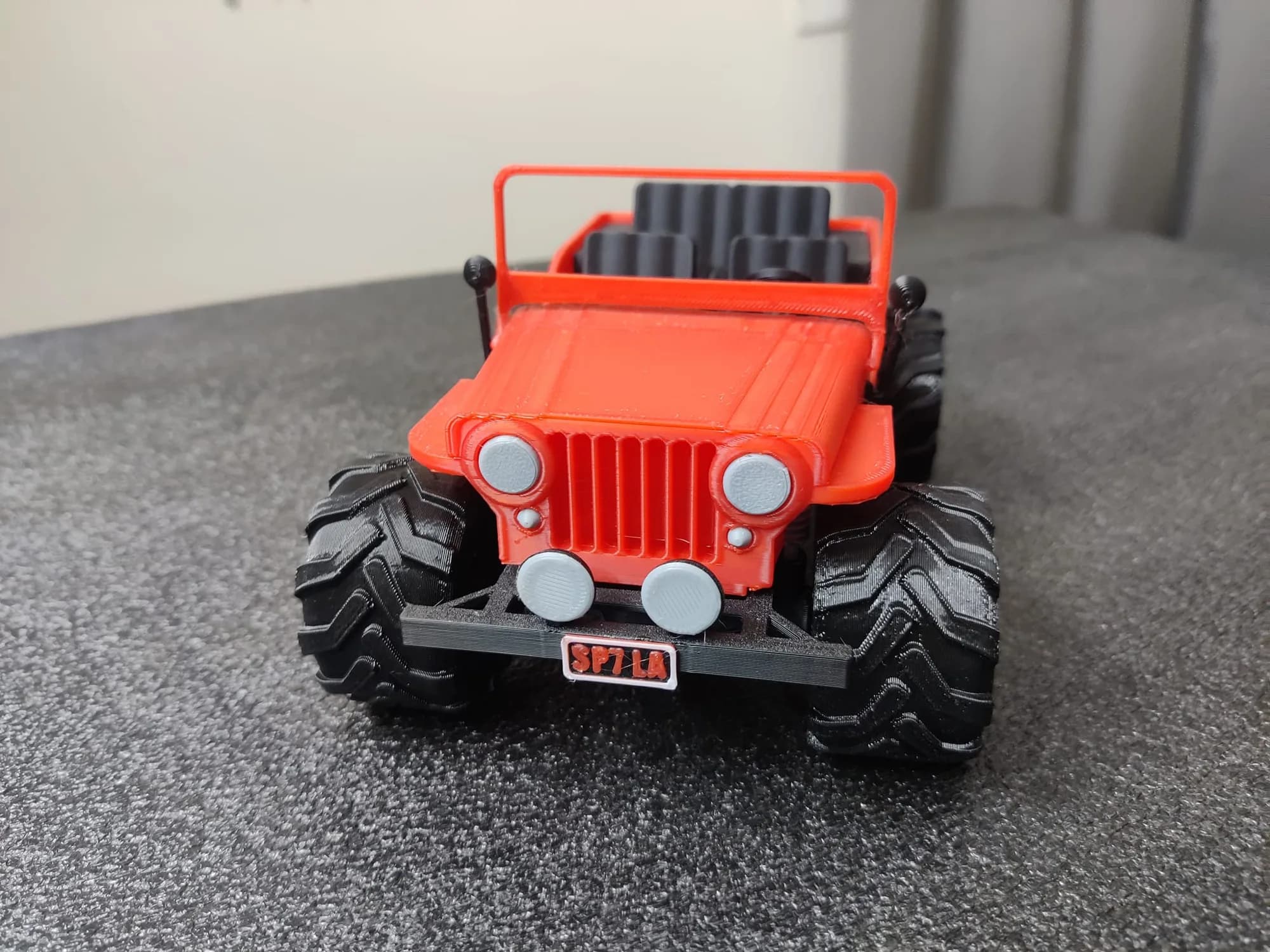 Straight-on front view of the red jeep model with its number plate and windscreen frame