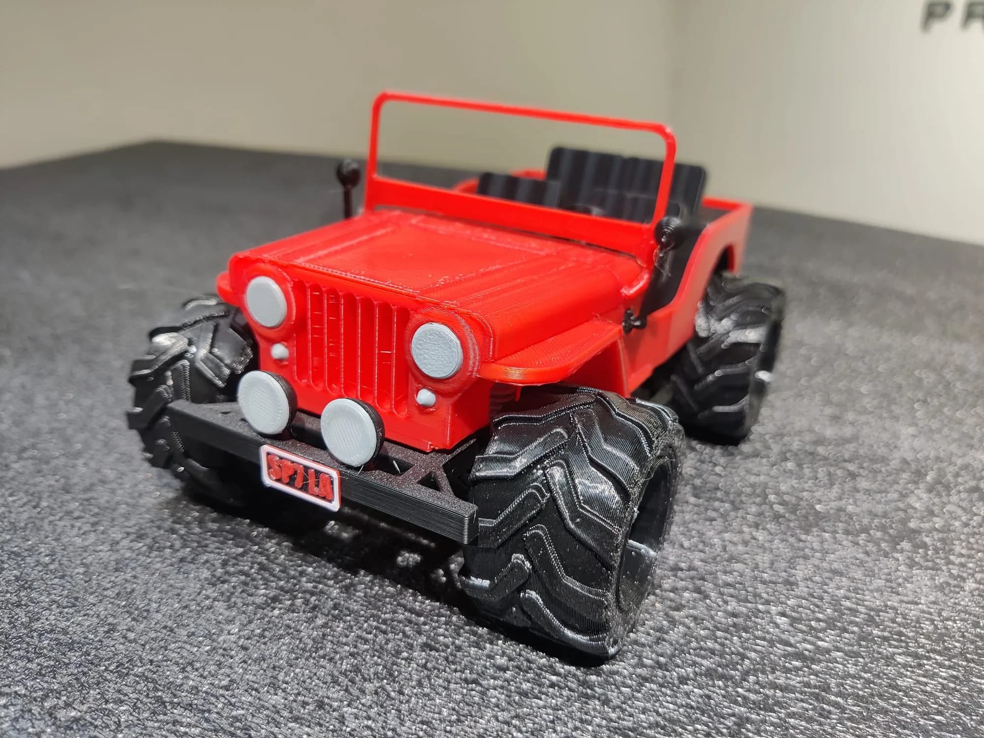 Close view of the jeep model's slotted grille, grey headlights, spotlights and chevron-tread tyres