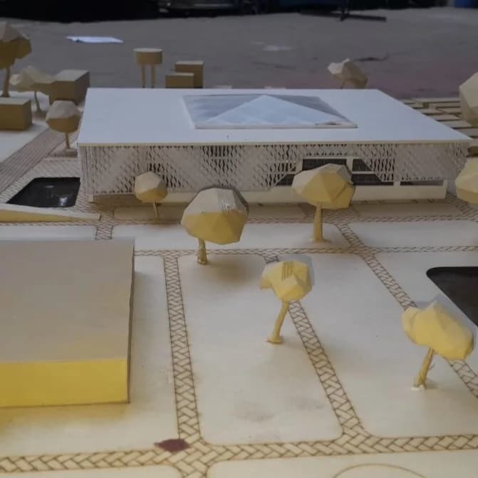 Engraved footpaths with brick-pattern edges running between 3D printed trees in front of the library model