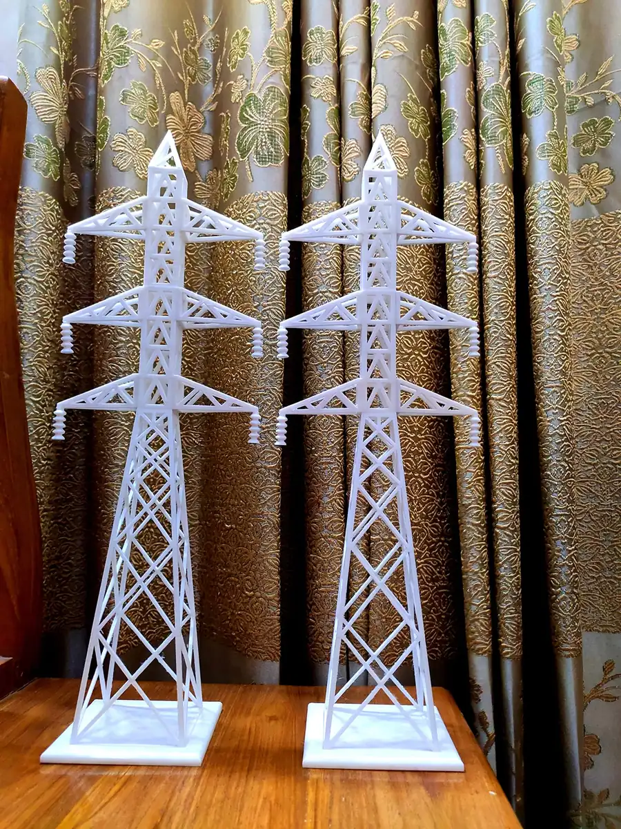 Two white 3D printed lattice transmission tower models with three cross-arms each, on square bases