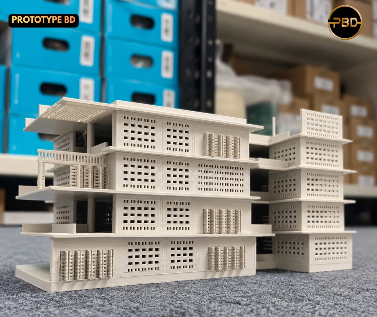 White multi-storey architectural building model with perforated facade panels, 3D printed in plastic and photographed on a grey carpet