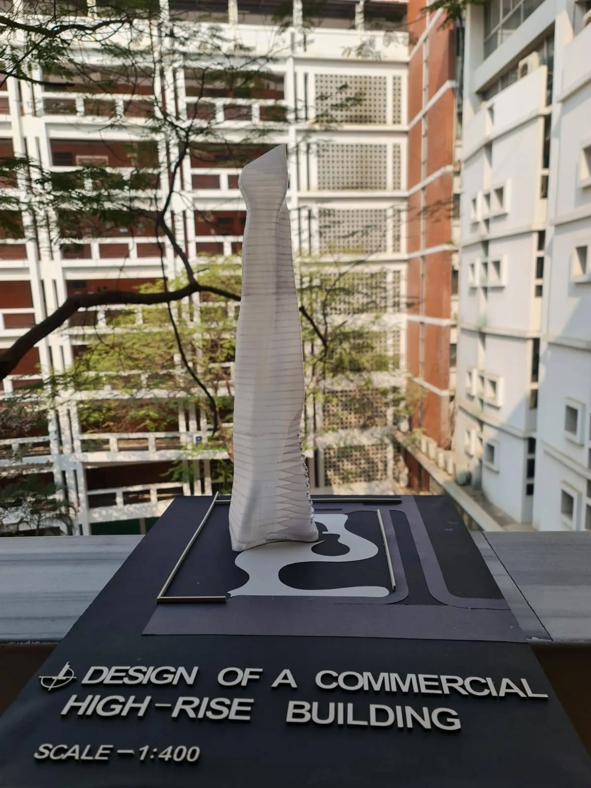 Twisting white tower model on a dark site base labelled as a commercial high-rise building at scale 1:400