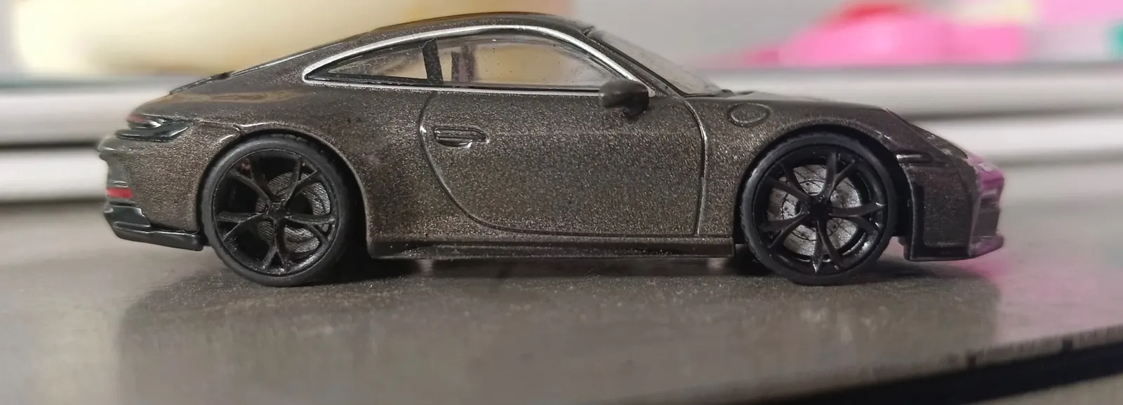 Side view of a dark grey die-cast model car fitted with black multi-spoke wheels