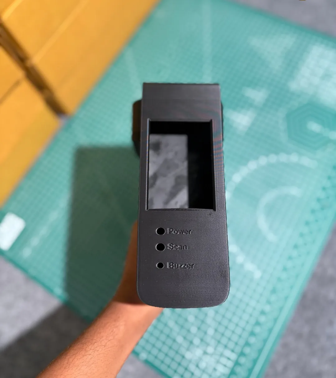 Black 3D-printed handheld ID card verifier with a display opening and holes labelled Power, Scan and Buzzer