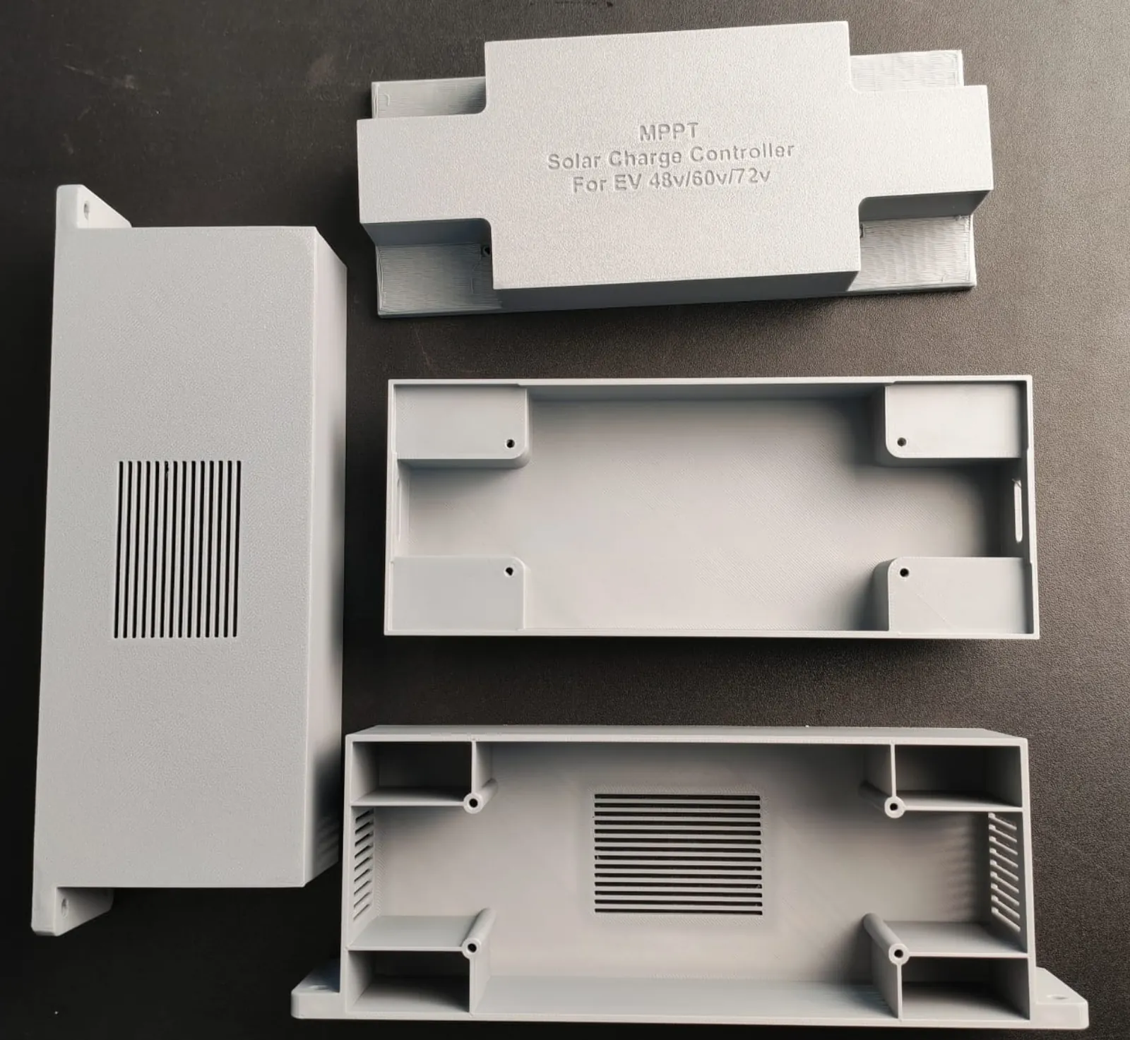 Grey 3D-printed MPPT charge controller enclosure parts: lettered lid, box halves with corner screw bosses, vented side cover