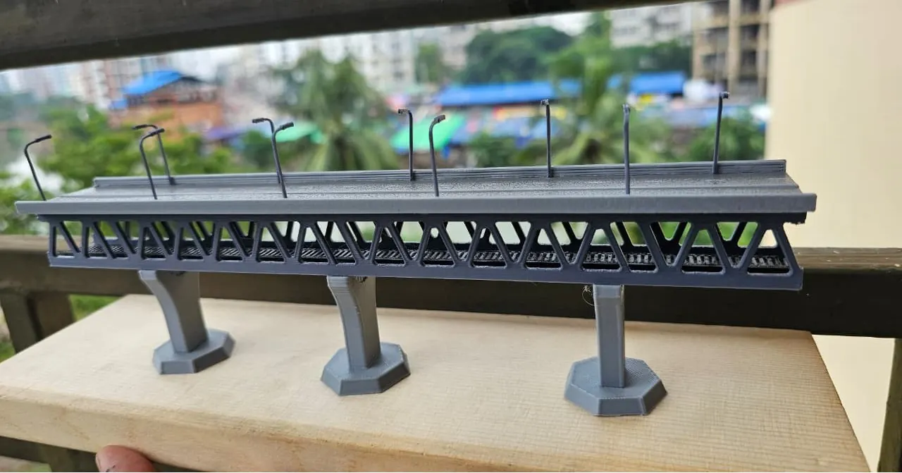 Grey 3D printed bridge miniature with a lattice truss under the road deck, three piers and lamp posts