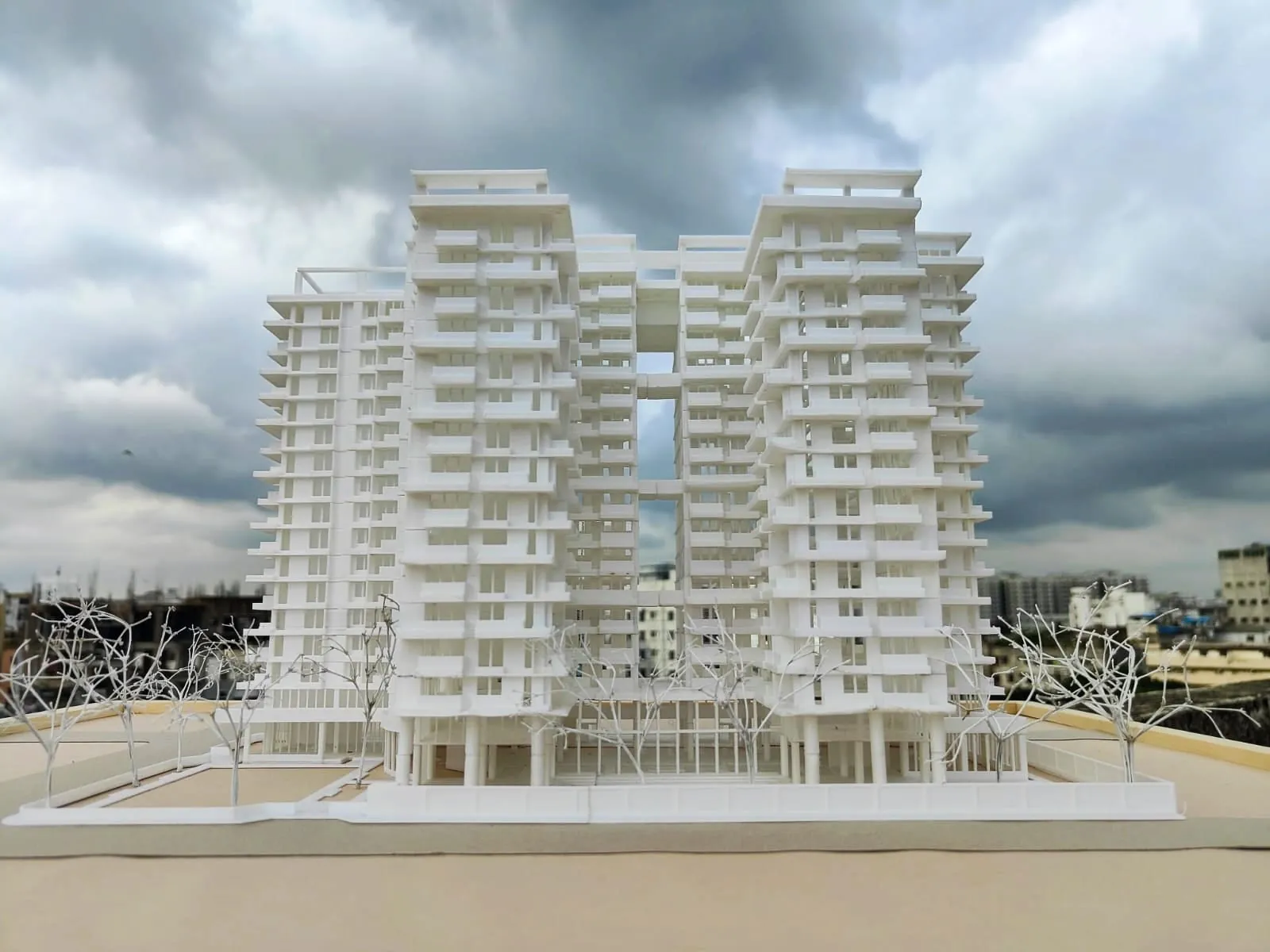 White 3D-printed model of linked high-rise housing towers with balconies, photographed on a rooftop