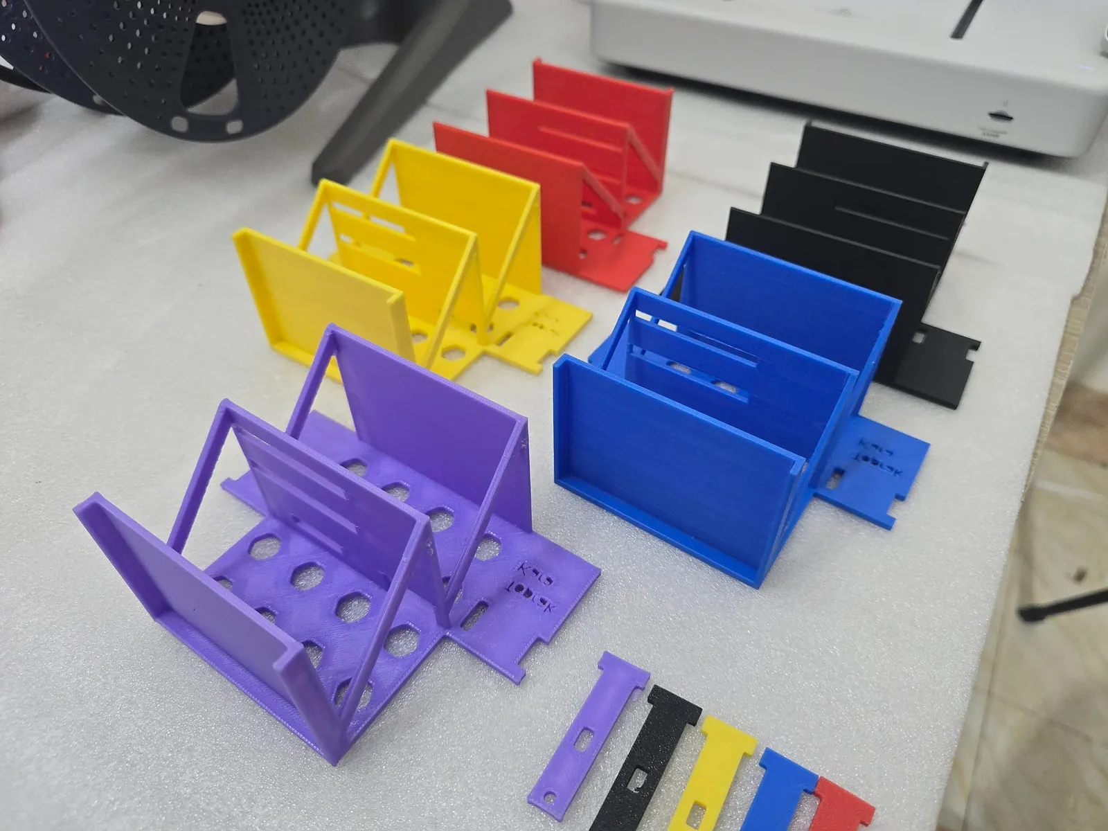 Purple, yellow, blue, red and black 3D printed body parts of a self-balancing Arduino robot laid out on a table